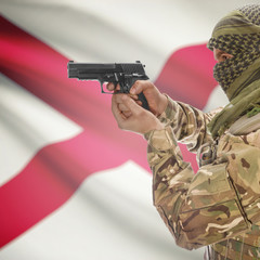 Fototapeta premium Side view of man in camouflage holding gun against flag of Alabama