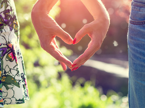Young couple in love holding hands on the sunset during summer evening