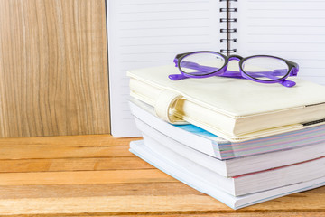 A lot of books with purple glasses on a wooden table