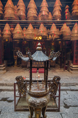 Urn with burning incense sticks and incense cones at the Man Mo Temple in Tai Po, Hong Kong, China.