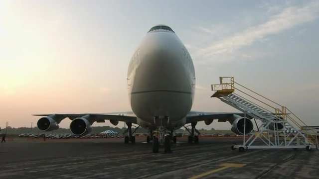 Tilt up to a wide view of the front of a Boeing 747 Jumbo Jet parked at airfield at dawn.  Recorded in 4K, ultra high definition.