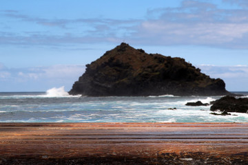 Fototapeta na wymiar Holzauflage vor Küstenlandschaft mit Felsen