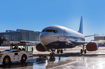 TUG Pushback tractor carries a passenger jet in hangar.