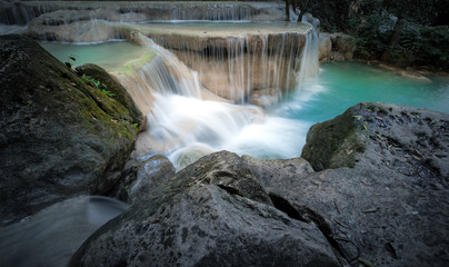 Rapid mountain river stream with cold fresh water running and falling from small waterfalls surrounded by wet stones and rocks