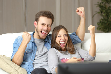 Euphoric couple watching tv at home