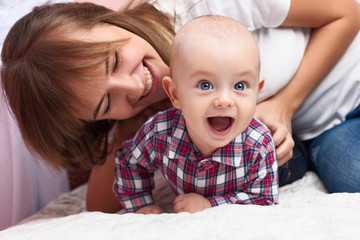 Portrait of smiling young beautiful woman playing with cute baby. Happy family concept