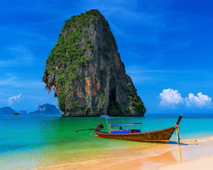 Wooden boat on exotic sandy beach with tropical sea at summer in Thailand