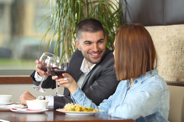 Happy young couple in love toasting while having a lunch at the restaurant