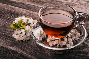   cup of tea with spring flower cherry blossom on a wooden rustic background. Vintage style.