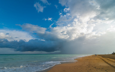 Fototapeta na wymiar A fast moving and blustery rain blows over a vacant Varadero beach in the morning. Dramatic clouds mixed with blue sky over the land and sea.