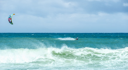 Big sea waves and kite-surfer enjoying extreme water sport