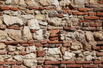 old wall of stones and red bricks with lime and cement