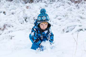Fototapeta na wymiar Happy child having fun with snow in winter