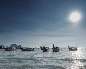Beautiful photograph of many fishing boats on sea with bright sun shining on blue sky