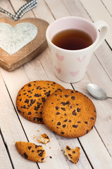 Tea, cookies and wooden heart. Composition on a light wooden background
