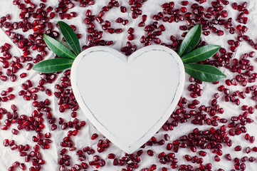 The heart and pomegranate seeds on the white background. Top view