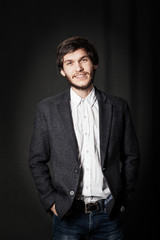 Young man standing and looking forward. Dark background.