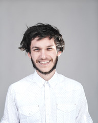 Cheerful young man with a messy hairdo. Light background.