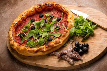 pizza with anchovies black olives and arugula