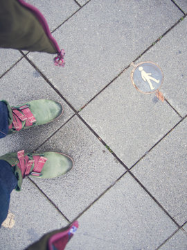 Selfie von grünen Stiefeln auf grauem Betonpflaster mit Fußgänger-Plakette