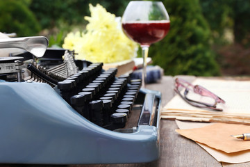Vintage black typewriter on decorated wooden table, outdoors, close up
