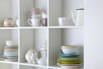 Different clean dishes on wooden shelves