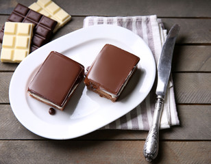 Delicious chocolate brownies on plate, on wooden background