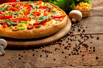 Delicious pizza with vegetables on wooden background