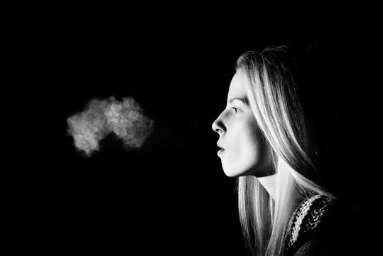 Woman Smoking a Cigarette on Black Background