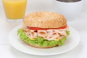 Bagel Brötchen zum Frühstück mit Schinken, Kaffee und Orangen
