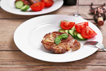 Roasted beef fillet and fresh vegetables on plate, on wooden background