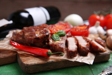 Roasted beef fillet and vegetables on cutting board, on wooden background