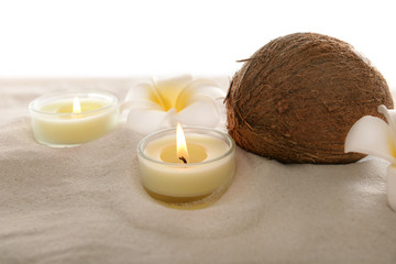 Fototapeta na wymiar Coconut with plumeria and candles on sand, isolated on white