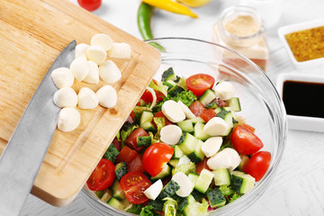 Adding mozzarella cheese to salad, at kitchen