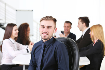 Photo of a young business man with his staff at the meeting in a conference room