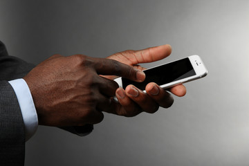 Afro american man holding smartphone on grey background