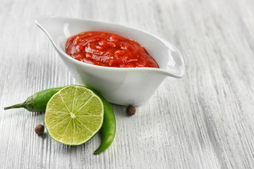 Homemade hot sauce and spices on light wooden background