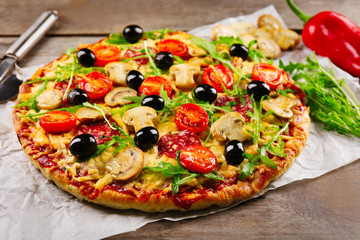 Delicious tasty pizza with cutter and ingredients on wooden table