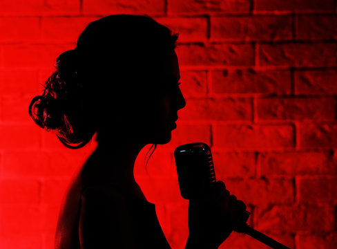 Silhouette of singing woman  on brick wall background