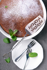 Chocolate pie with sugar powder and kitchenware, closeup