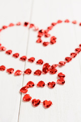 The figure in the shape of a heart made of red string on the wooden table