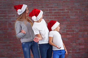 Boys and girl in Santa hats in a row on brick wall background