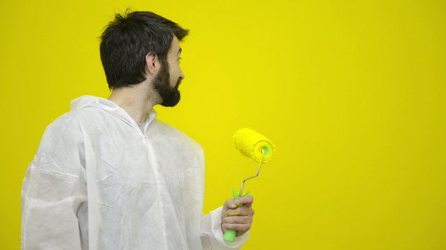 Man is gesturing with a yellow paint roller