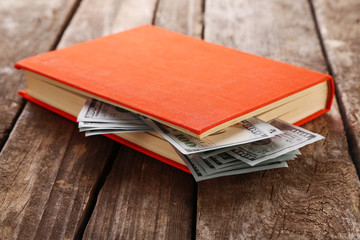 Book with nested dollar banknotes on wooden table. Stash of money