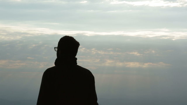 Man silhouette on mountain at sunrise is enjoying the panorama   