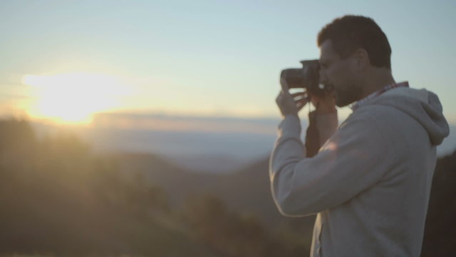 Man shoot photos with camera at sunrise or sunset   