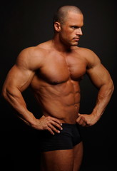 Fototapeta na wymiar Muscular man poses on gray background