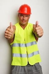 Muscular builder in a protective helmet shows you thumbs up