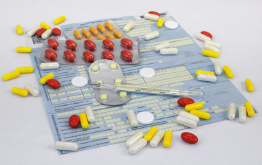 pills, thermometer and a sick-list on a white background