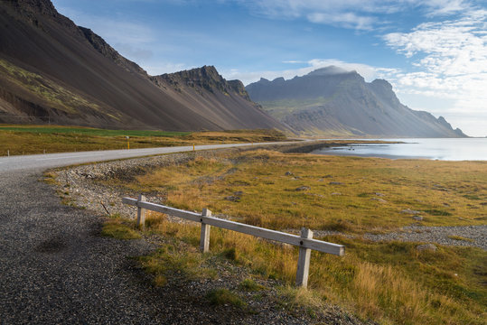 Abandon timber fence at coast road with mountain range background in shiny day Autumn season Iceland